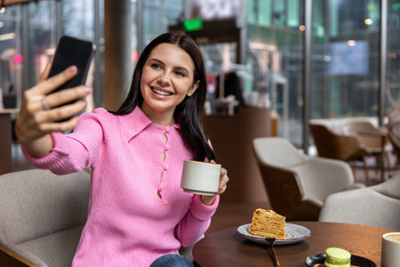 A girl in a pink shirt sitting in a cafe and feeling positiveの写真素材