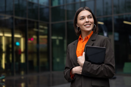 Cute young woman with a gadget in the office area looking contentedの写真素材