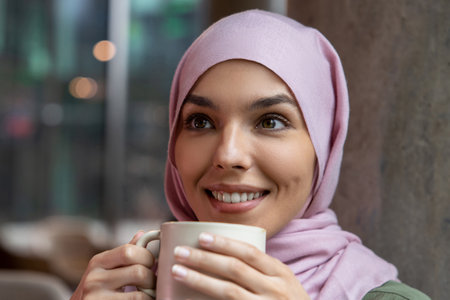 Pretty young smiling muslim woman enjoying her coffee