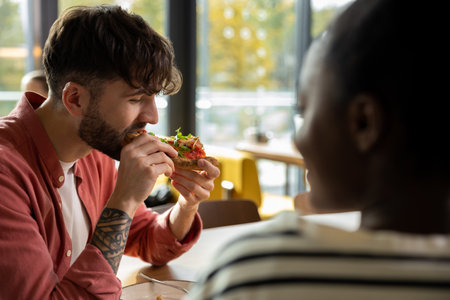 Young couple having pizza in a cafe and looking enjoyedの写真素材