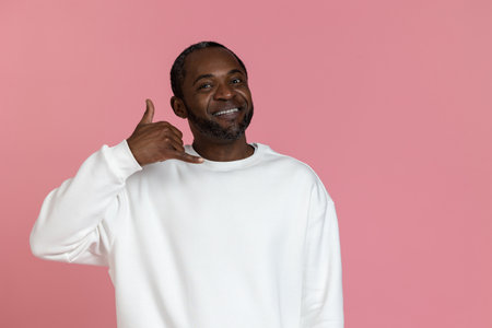 Handsome black man wearing white sweatshirt showing call me gestureの写真素材