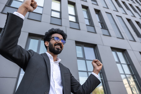 Waist up of an excited successful hindu businessman near the office buildingの写真素材