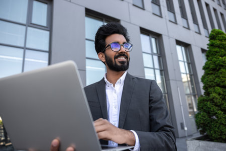Brunette young businessman working on laptop and feeling contented