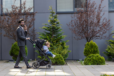 Young elegant man with baby carriage talking on the phone