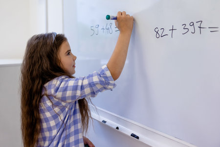Little girl counting math equation on whiteboard in school.