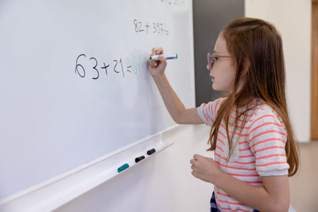 Little girl counting math equation on whiteboard in school.