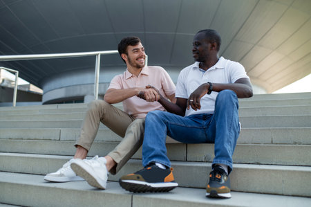Two colleagues sitting together on steps and talking