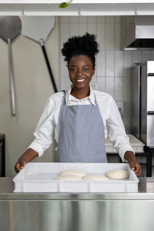 African american young woman preparing pizza in the kitchenの写真素材