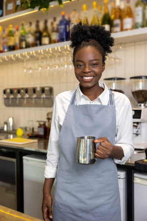 Smiling dark-skinned female barista with a coffee potの写真素材