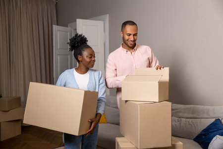 Man and woman relocating to a new house holding cardboard boxes with belongings
