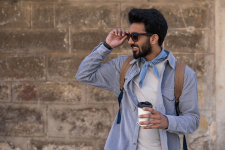 Smiling positive hindu man with a cup of coffee in hands