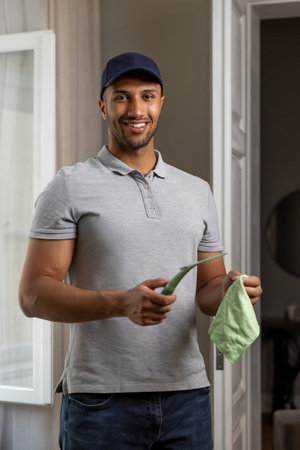 Man washing window doing household chores at home holding wiper squeegee and rag.
