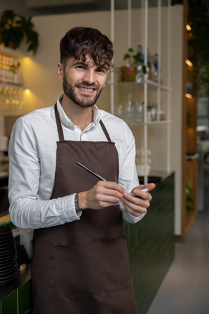 Pizzeria worker in apron making notes for order preparation