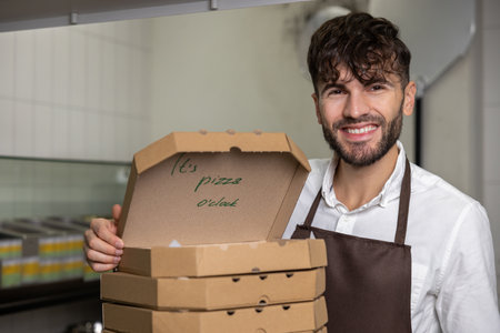 Male service man with many pizza boxes in pizzeriaの写真素材