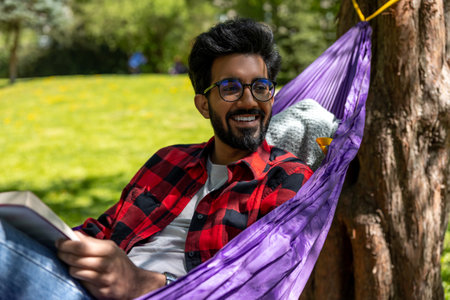 Hindu young man enjoying a day in a park while laying in hammockの写真素材