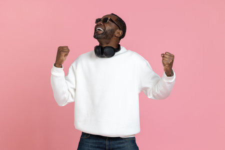 Overjoyed happy black man wearing white sweatshirt clenched fists