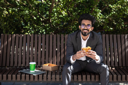 Businessman sitting on the bench and having his lunchの写真素材