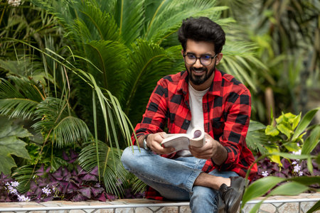 Hindu young man sitting in the garden with a book in handsの写真素材