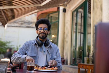 Young hindu man eating pizza in pizzeriaの写真素材