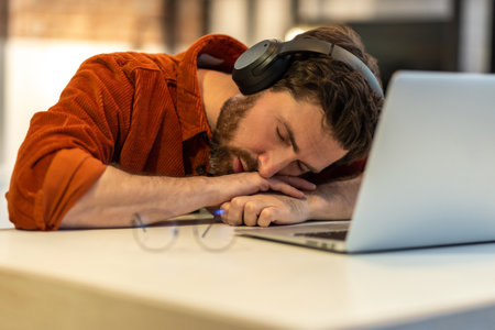 Man in headphones napping at laptop