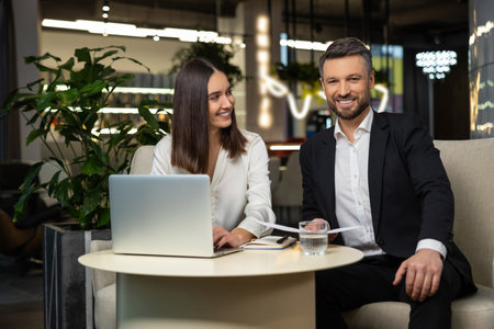 Young man and woman sitting at the table and working togetherの写真素材