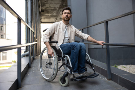 Dark-haired young caucasian man riding a wheelchair