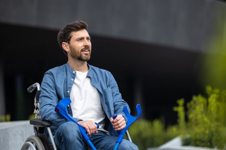 Bearded young man with sticks on a wheelchairの写真素材