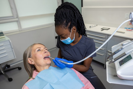 Woman patient sitting in dental chair at medical center while professional doctor fixing her teeth