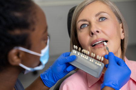 Woman dentist holding dental teeth shade guide chart choosing right enamel color for female patientの写真素材