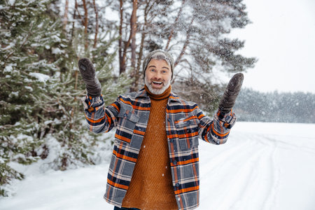 Man in checkered jacket feeling good while spending time in a winter forestの写真素材
