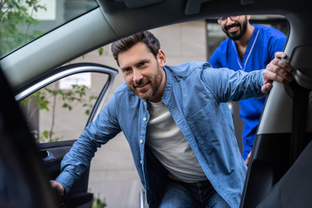 Disabled man getting on a car, male nurse helping himの写真素材