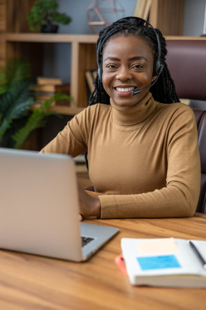 Professional businesswoman with dreadlocks in headphones uses laptop for online tutoring
