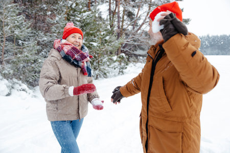 Mature couple playing snowballs and looking enjoyedの写真素材
