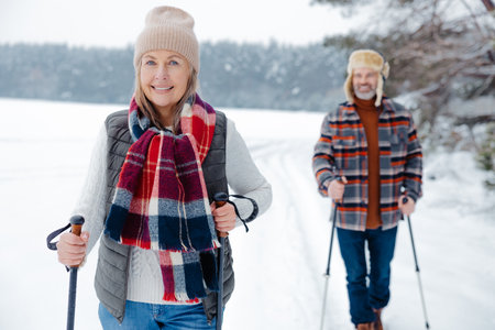 Happy mature couple with scandinavian stick on a walk in a forest
