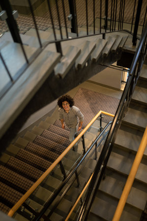 Top view of a curly-haired man coming downstairs