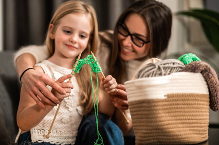 Mother and little daughter knitting together while having leisure time