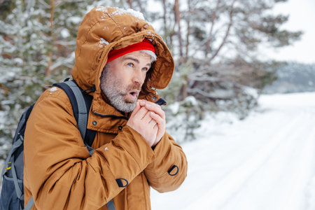 Man in warm jacket getting cold in a winter forest