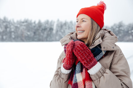 Smiling mature woman in red hat having hot tea outdoors