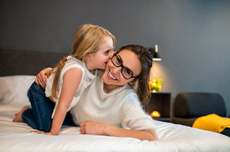 Happy mother and little daughter cuddling on cozy bedの写真素材