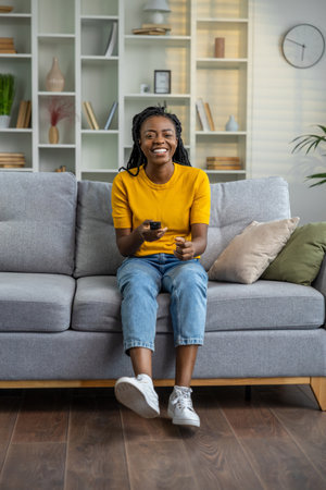 Young african american woman sitting on the sofa at home
