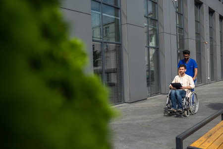 Disabled man having a walk with a male nurse and reading his prescription leaflet
