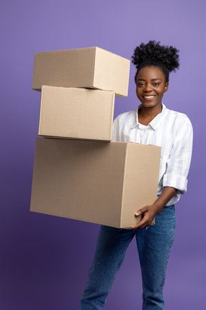 Dark-skinned young woman with boxes in hands looking contented