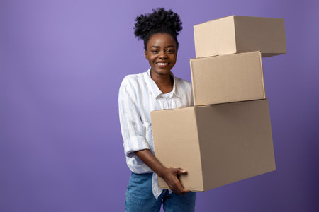 Dark-skinned young woman with boxes in hands looking contented