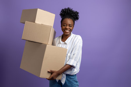 Dark-skinned young woman with boxes in hands looking contentedの写真素材