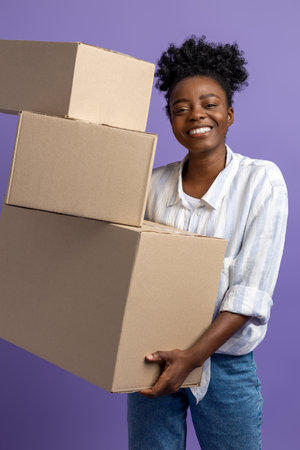 Dark-skinned young woman with boxes in hands looking contented