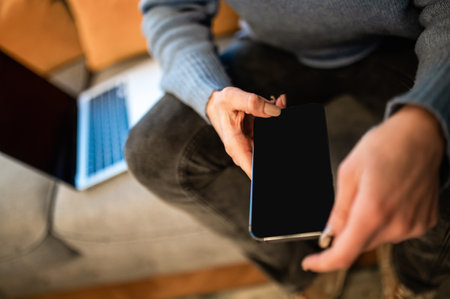 Unrecognizable woman holding mobile phone with black blank screen copy space