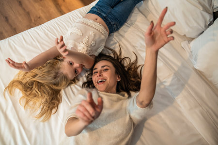 Woman and her daughter in bedroom with candle having fun togetherの写真素材