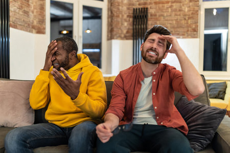 Two men looking disappointed while watching a football match