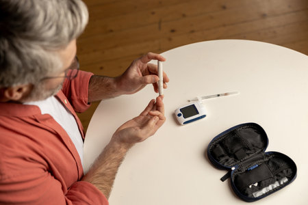 Unhealthy diabetic man checking level of sugar in blood with glucometerの写真素材
