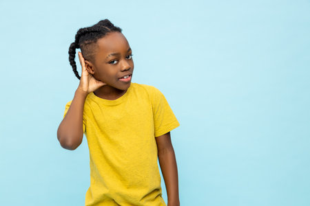 Serious curious dark- skinned little boy hearing something